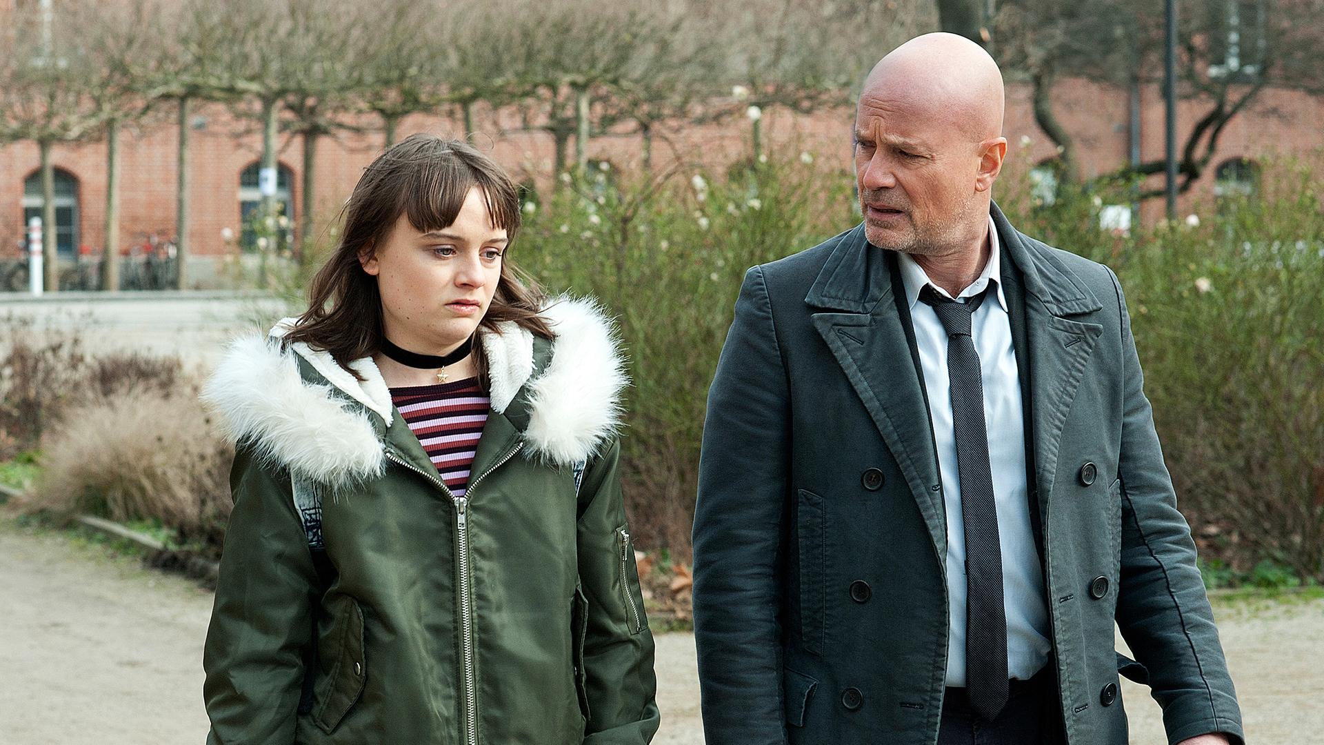 Bruno Schumann (Christian Berkel) und Danny Torrenz (Lena Urzendowsky) laufen einen gepflasterten Weg entlang