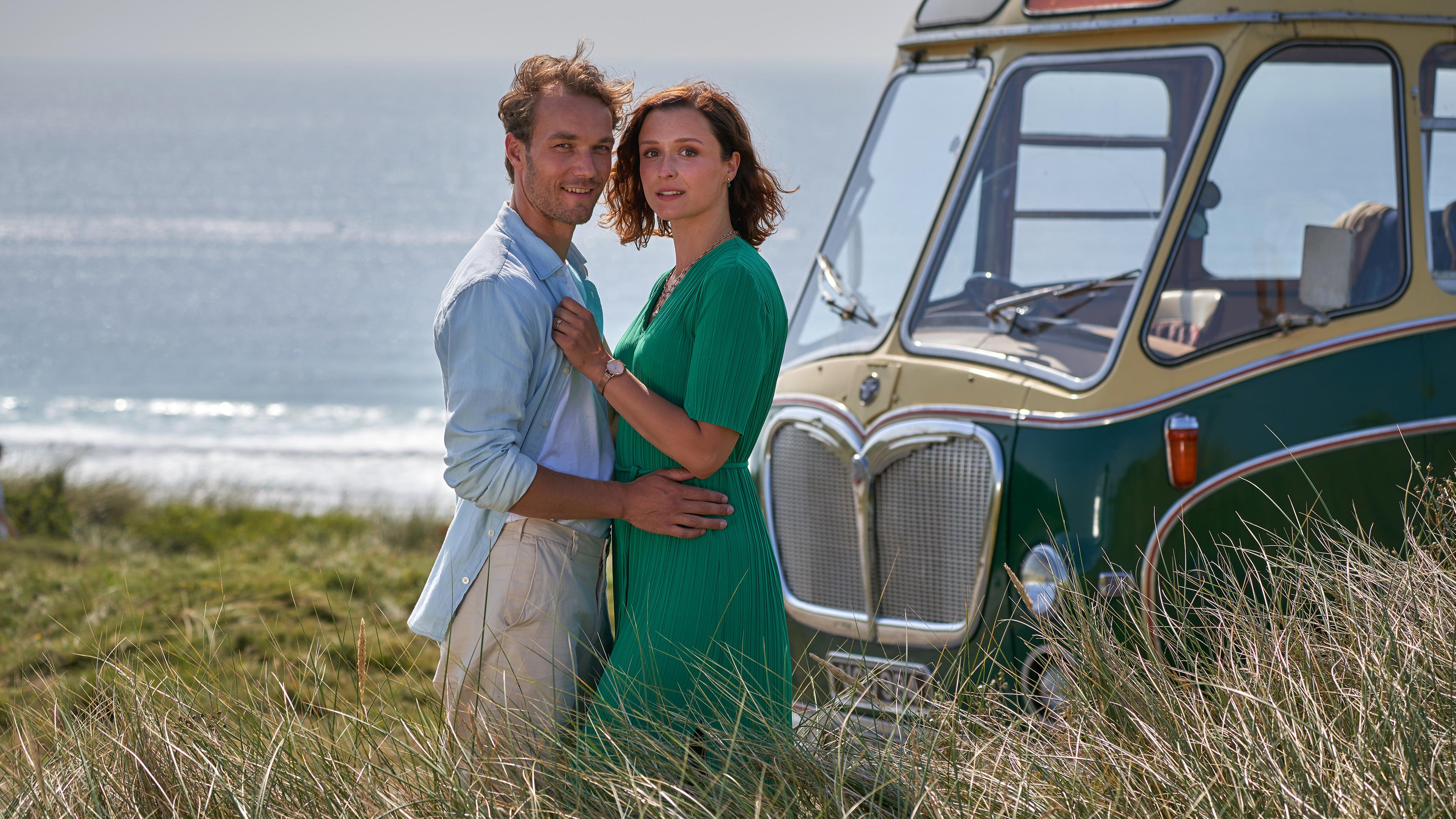 Nicolas (Max Woelky) und Olivia (Isabella Krieger) stehen im Dünengras am Meer und halten sich gegenseitig im Arm.