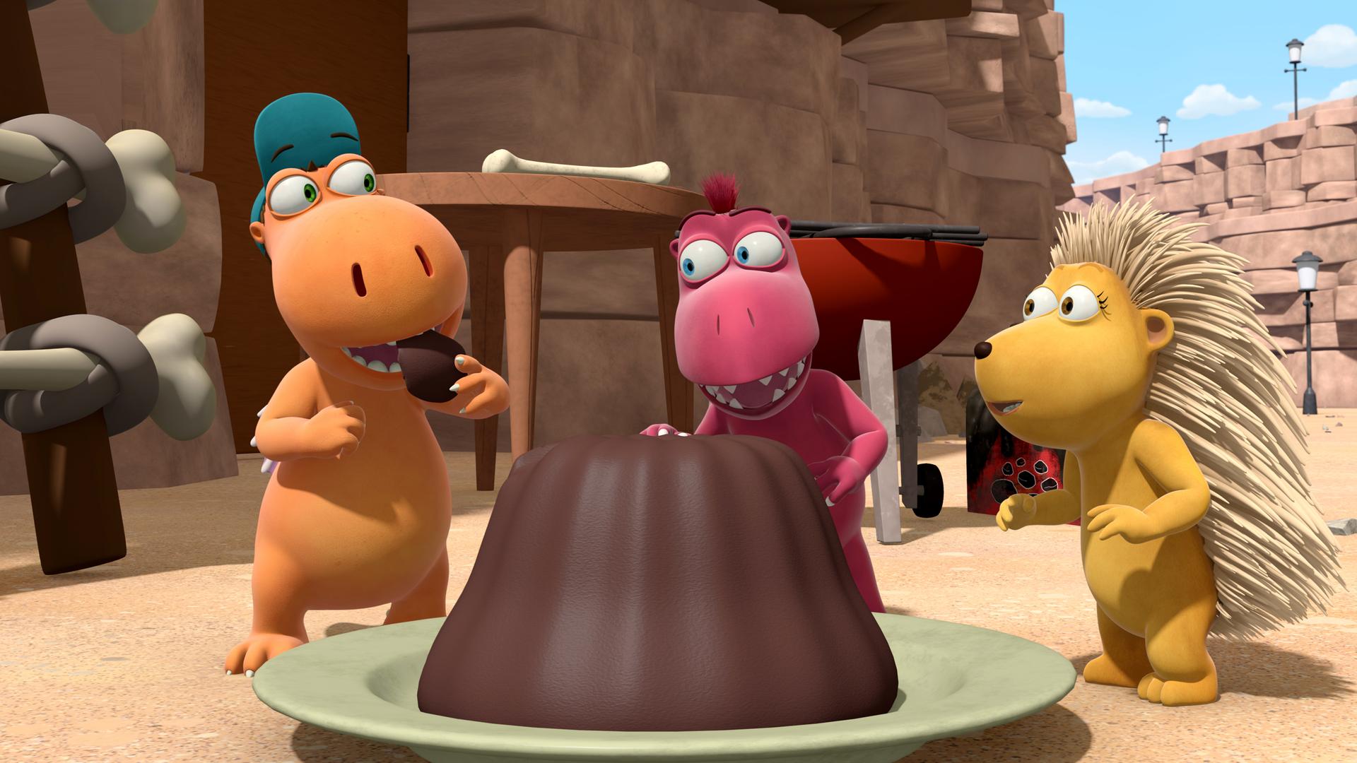 Kokosnuss, Oskar und Matilda stehen um einen großen Kuchen herum. Kokosnuss steckt sich gerade ein Stück davon in dem Mund.