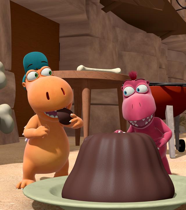 Kokosnuss, Oskar und Matilda stehen um einen großen Kuchen herum. Kokosnuss steckt sich gerade ein Stück davon in dem Mund.
