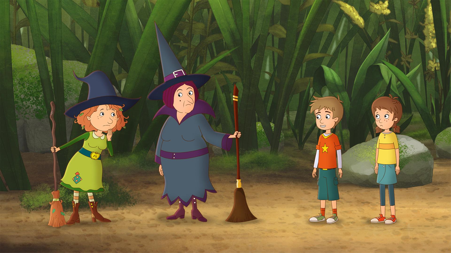 Oberhexe Pestilla steht mit ihrem kaputten Besen unglücklich neben Petronella und deren Besen, auf der anderen Seite stehen die Nachbars-Zwillinge Lea und Luis.