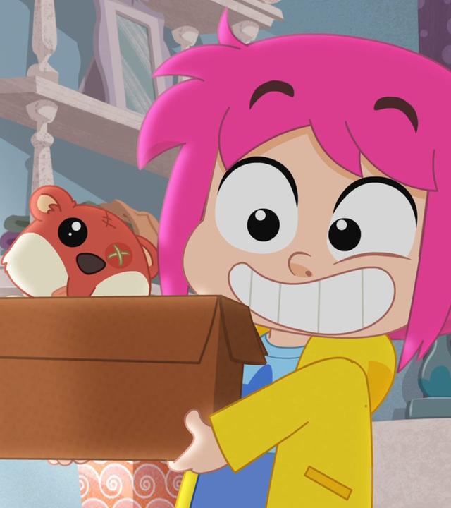 Rebecca hält grinsend eine braune Kiste hoch. Daraus guckt ein alter, mitgenommen aussehender Teddybär heraus.