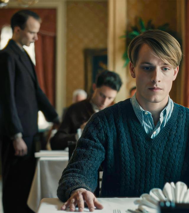 Junger Mann sitzt in einem Restaurant am Tisch.