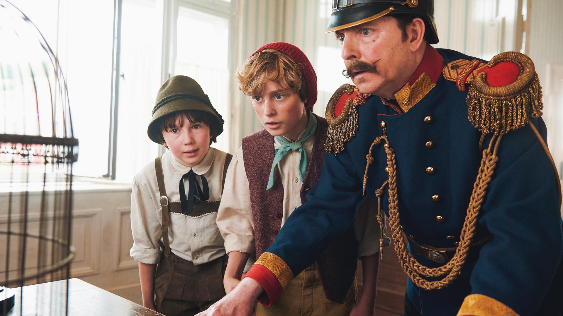 "Der Räuber Hotzenplotz": Seppel (Benedikt Jenke), Kasperl (Hans Marquardt) und Wachtmeister Dimpfelmoser (Olli Dittrich) stehen in der Wachstube vor einem Vogelkäfig und sehen verwundert hinein.