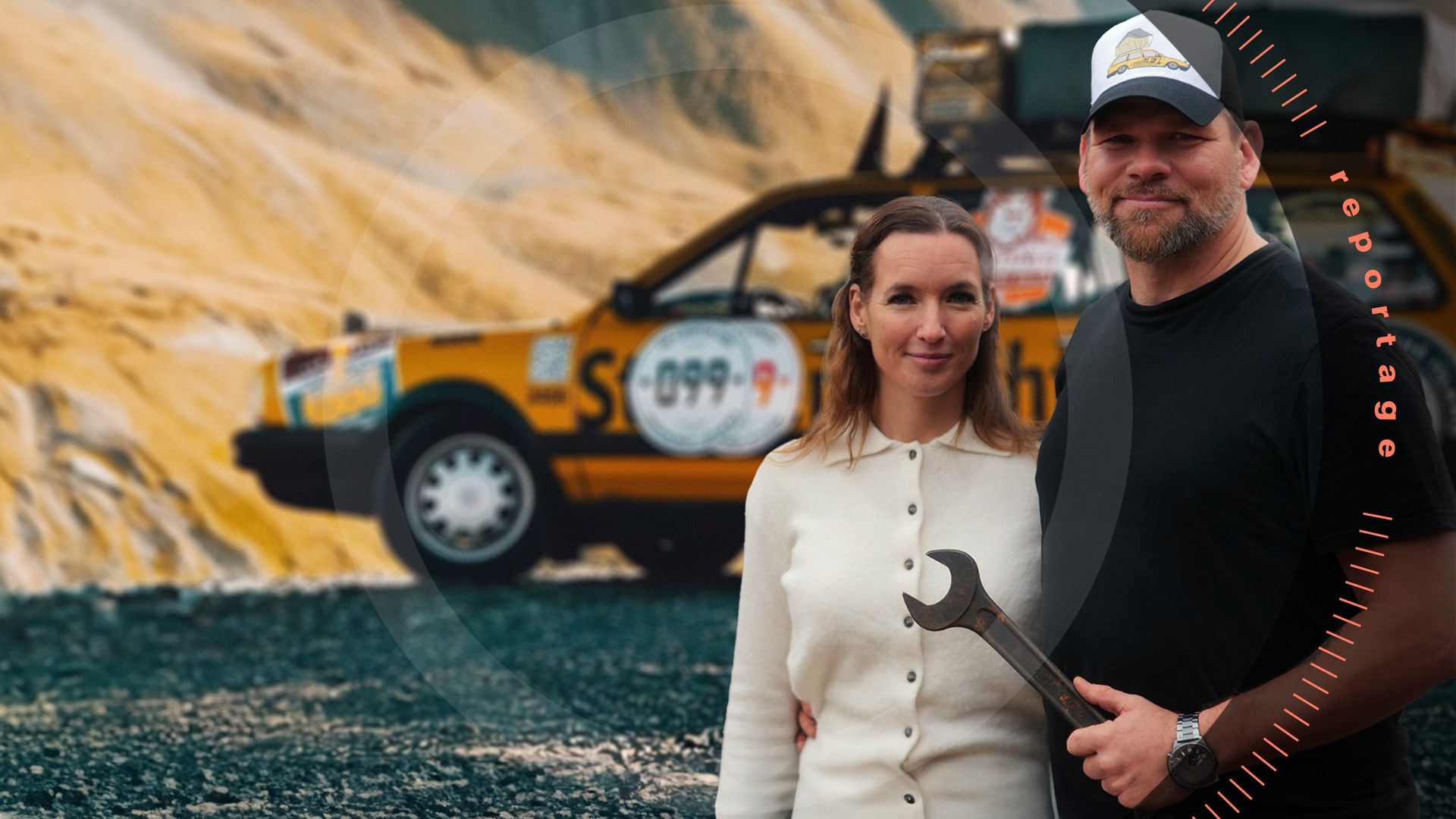 Hardy Leben und Freundin Jessica Hetke umarmen sich. Beide stehen vor ihrem zu einem Pannenhelfer-Auto umgebauten VW-Passat-Oldtimer. Hardy Leben hält einen großen Schraubenschlüssel in Hand. 