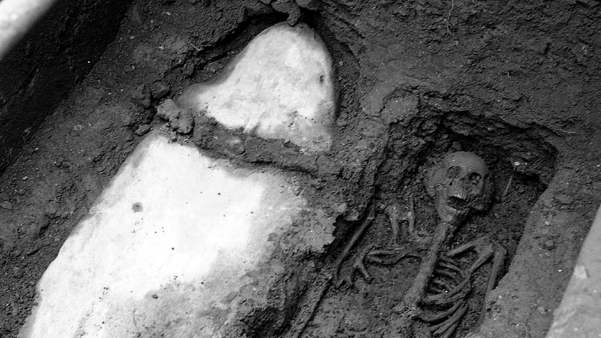 "Mysterien des Mittelalters - Der Ritter von St. Bees": Ein Skelett befindet sich freigelegt in einer Grube aus Erde. Daneben ist eine weitere Grube, in der ein in Leinen eingewickelter Körper liegt.