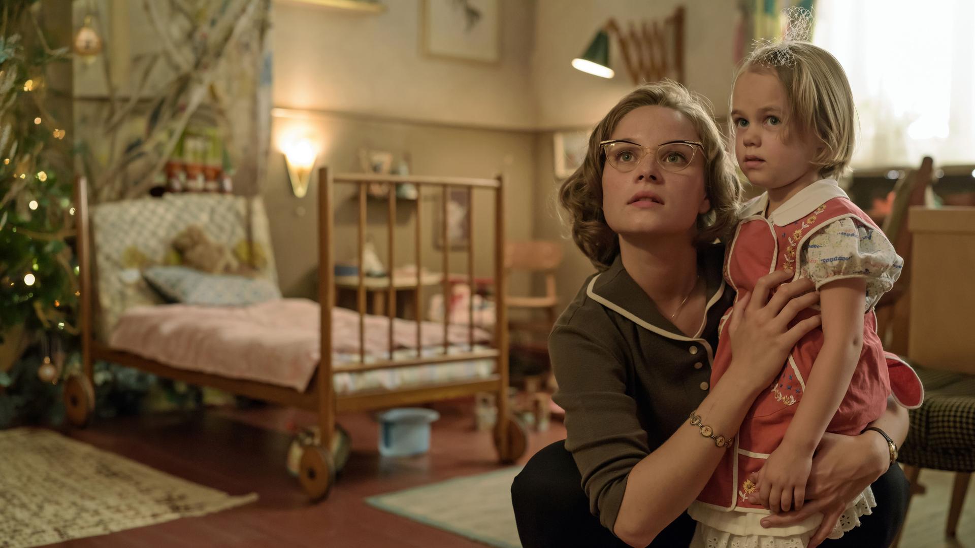 Monika Schöllack (Sonja Gerhardt, l.) hat ihre Tochter Dorli (Alma / Smilla Löhr, r.) im Arm. Im Hintergrund ist ein Kinderzimmer zu sehen.