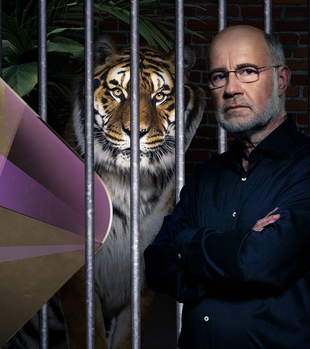Harald Lesch steht neben Tiger im Käfig