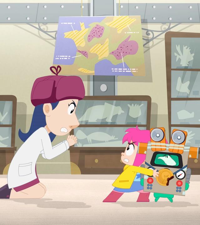 Eine Wissenschaftlerin bettelt Rebecca auf Knien an, den Roboter untersuchen zu dürfen. Ernest steht neben ihr. Er steckt in einem Pappkostüm und verfolgt die Aktion mit böser Miene.