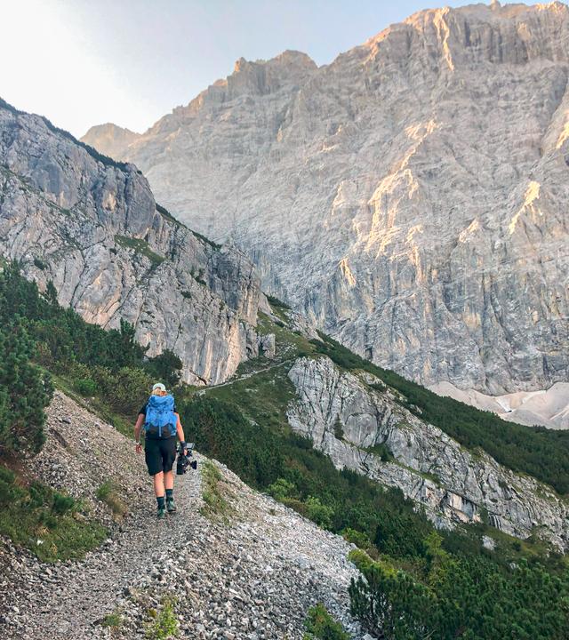Wanderin von hinten gesehen auf einem steinigen Bergpfad