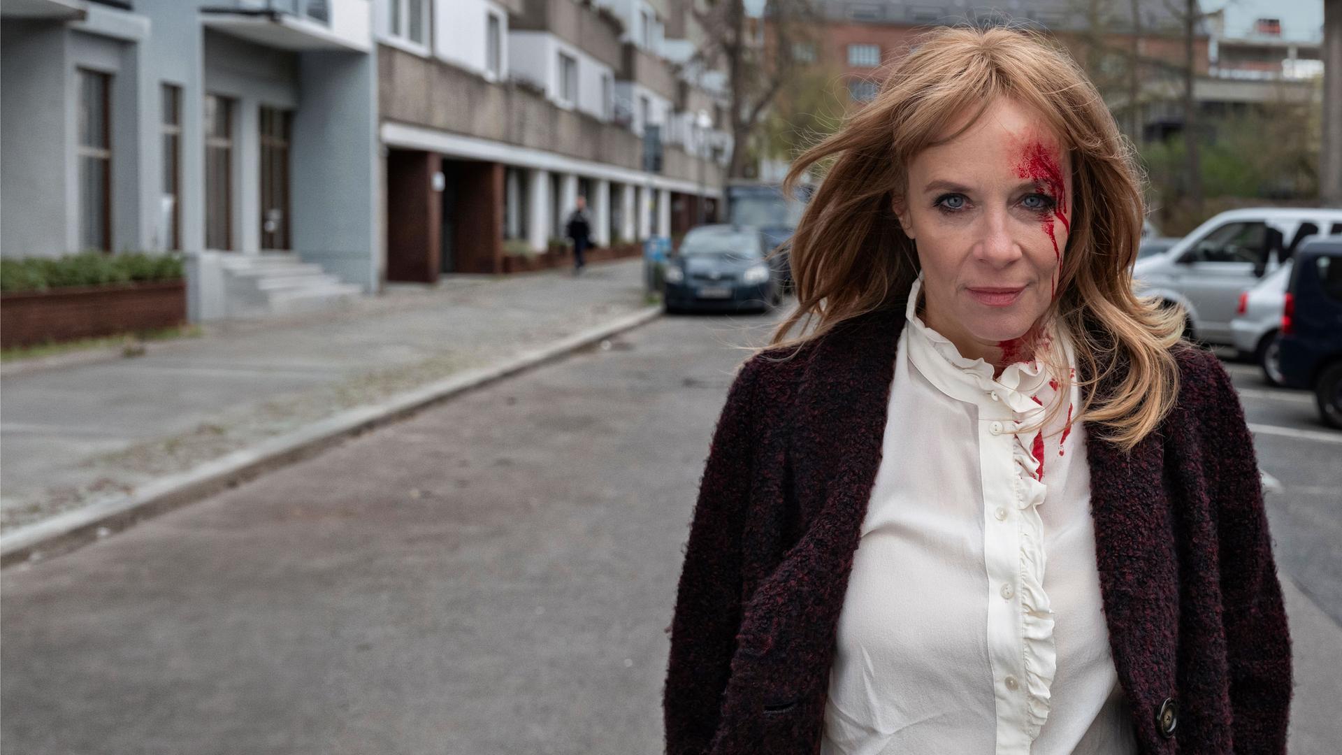 "Der Überfall - Sonnabend: Zwischen Leben und Tod": Paula Schönberg (Katja Riemann) läuft allein eine Straße herunter. Sie hat eine blutende Verletzung im Gesicht.