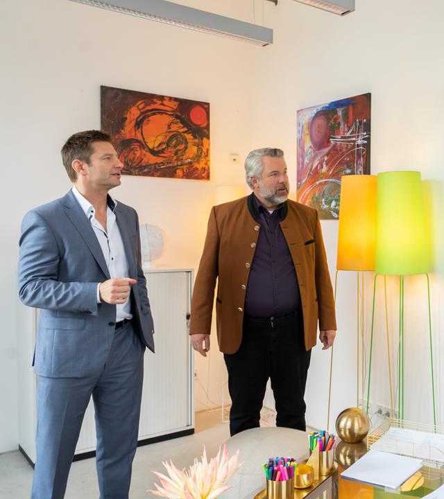 "Die Rosenheim-Cops - Der Unvollendete": Die Kommissare Hansen (Igor Jeftić) und Stadler (Dieter Fischer) stehen mit Professor Leonhard Bülow (Michael von Au) in dessen Zimmer und unterhalten sich. Im Hintergrund sind diverse moderne Gemälde zu sehen sowie zwei Stehlampen.