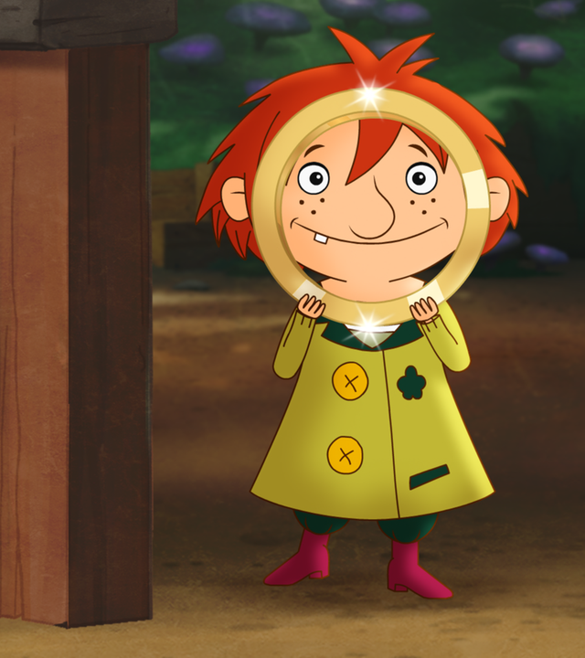 Wichtel Nisse schaut durch einen goldenen Ring hindurch, welchen er mit beiden Händen hochstemmt. Der Ring ist fast genauso groß, wie sein Kopf.