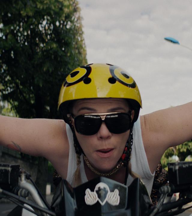 "Derby Girl": Eine Frau fährt auf einem Fahrrad. Sie trägt einen Helm und eine Sonnenbrille.