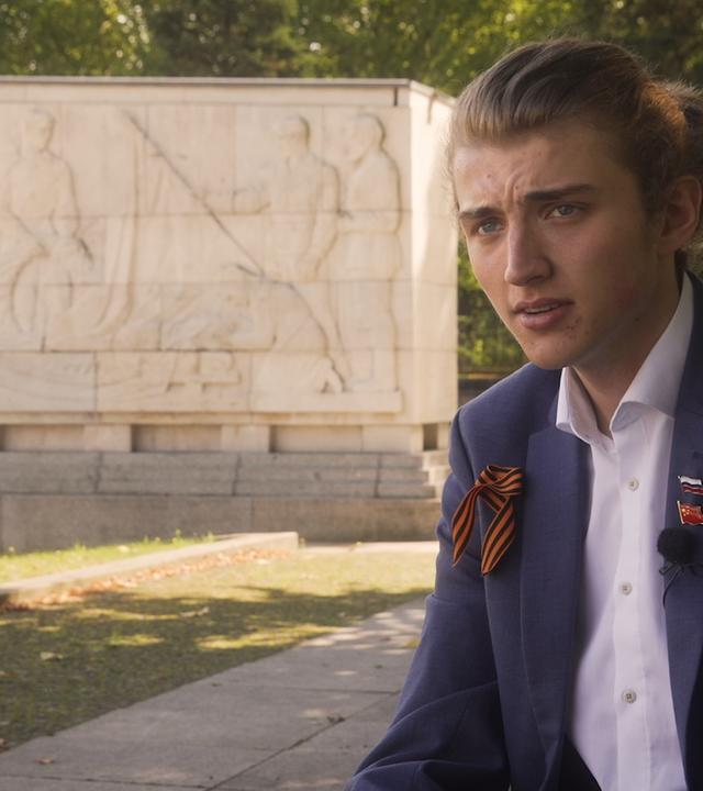 Junger Abiturient sitzt am Ehrenmal der Sowjetarmee im Treptower Park in Berlin