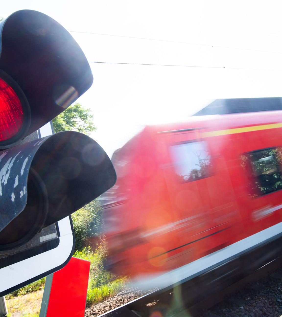 Eine S-Bahn der Deutschen Bahn (DB) fährt an einem Bahnübergang mit einer roten Ampel
