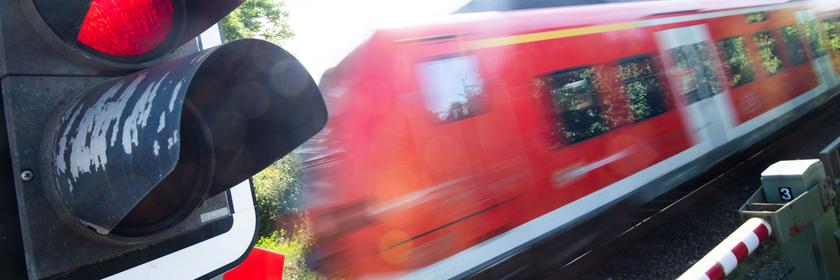 Eine S-Bahn der Deutschen Bahn (DB) fährt an einem Bahnübergang mit einer roten Ampel