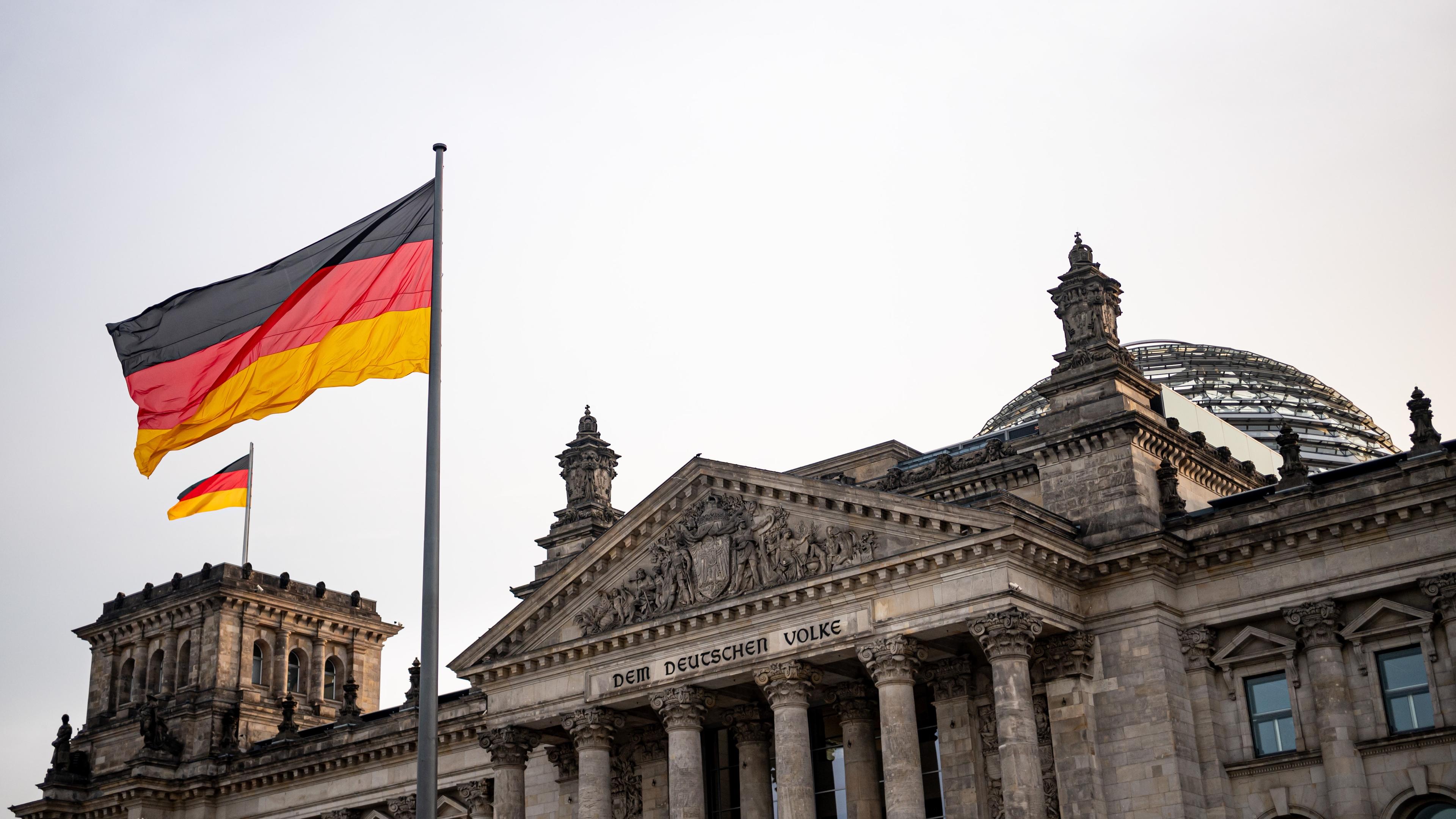 Reichstagsgebäude, davor eine wehende Deutschlandflagge