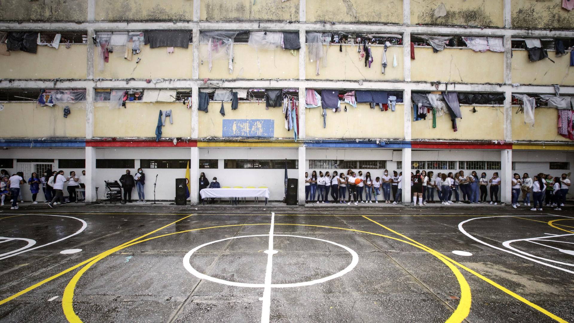 GInnenhof des Gefängnisses in Bogota, am Rand stehen mehrere Frauen. Aus den vergitterten Fenstern der Zellen hängt Wäsche.