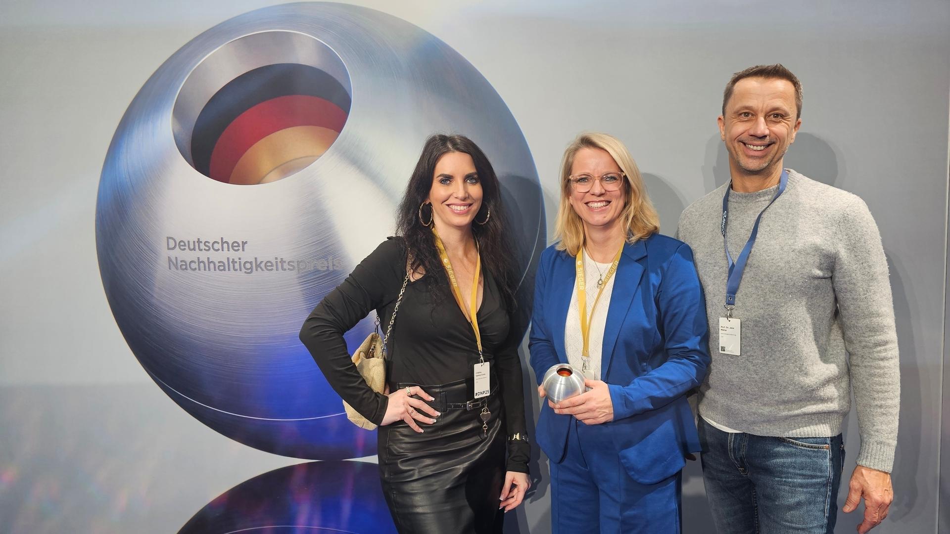 Das ZDF-Team für Nachhaltigkeit vor dem Logo des Deutschen Nachhaltigkeitspreises: Cristina Santos Couto, Tordis Koch und Jens Müller