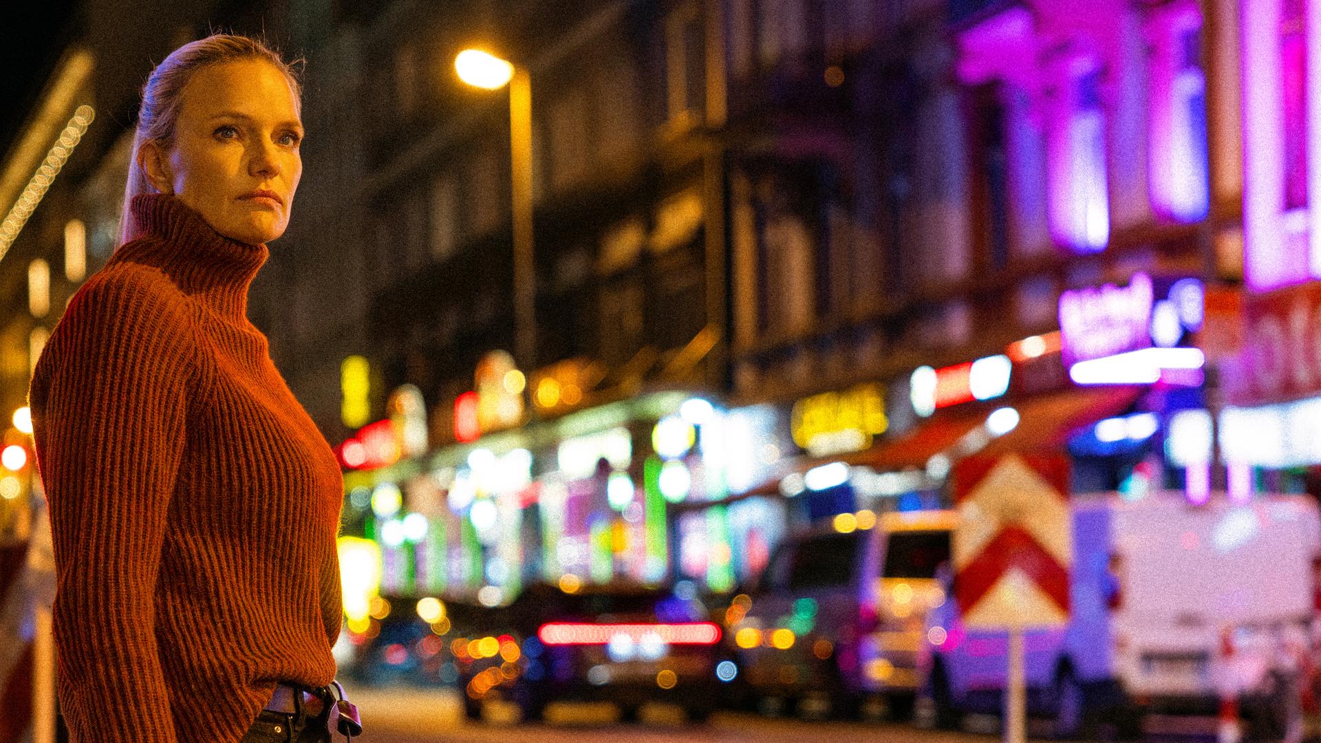 Sarah Tacke steht vor der Kulisse eines Rotlichtviertels irgendwo in Deutschland.