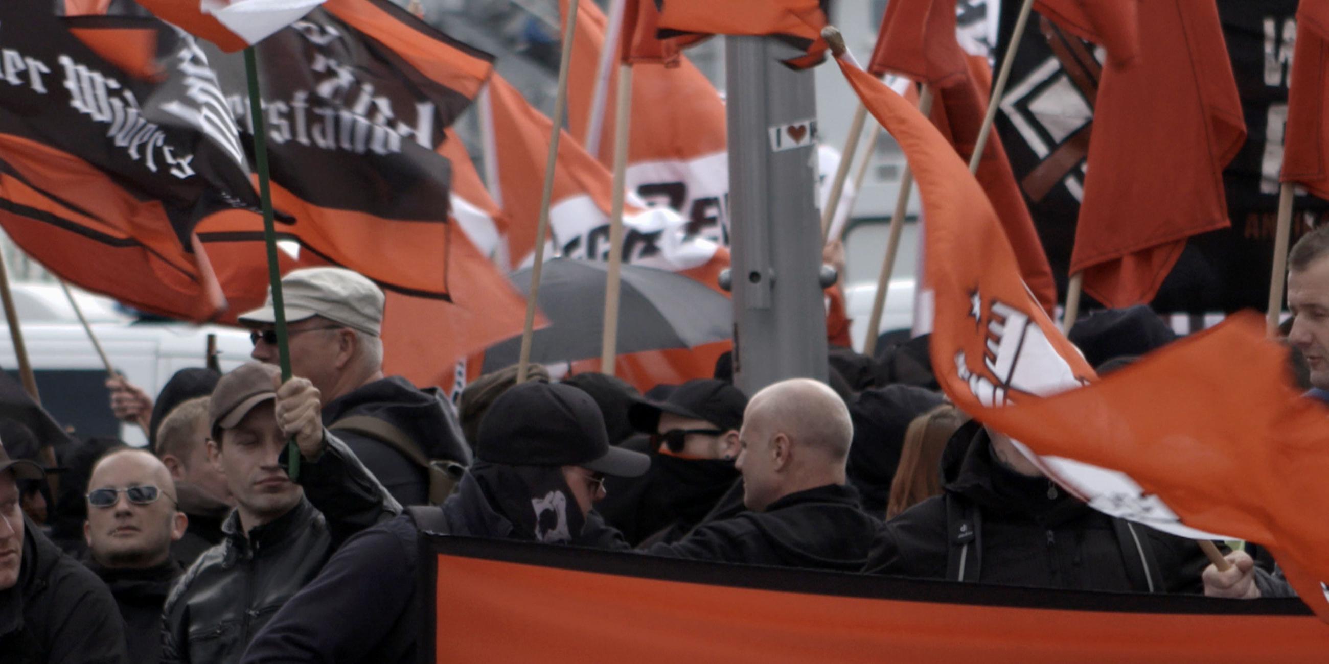 Rechte Demonstration zum 1. Mai in Halle. Viele schwarz gekleidete Menschen halten Fahnen mit Parolen hoch.