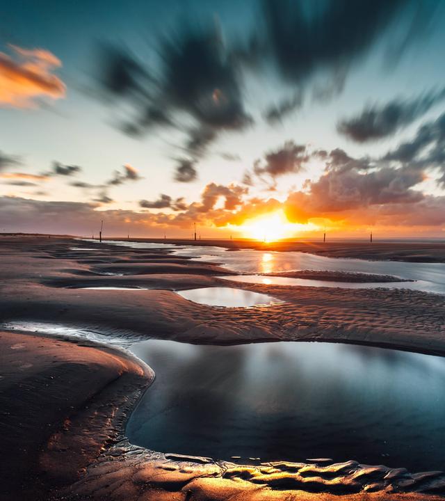 Sonnenuntergang im Wattenmeer Priele am Nordstrand von Norderney, Ostfriesland.