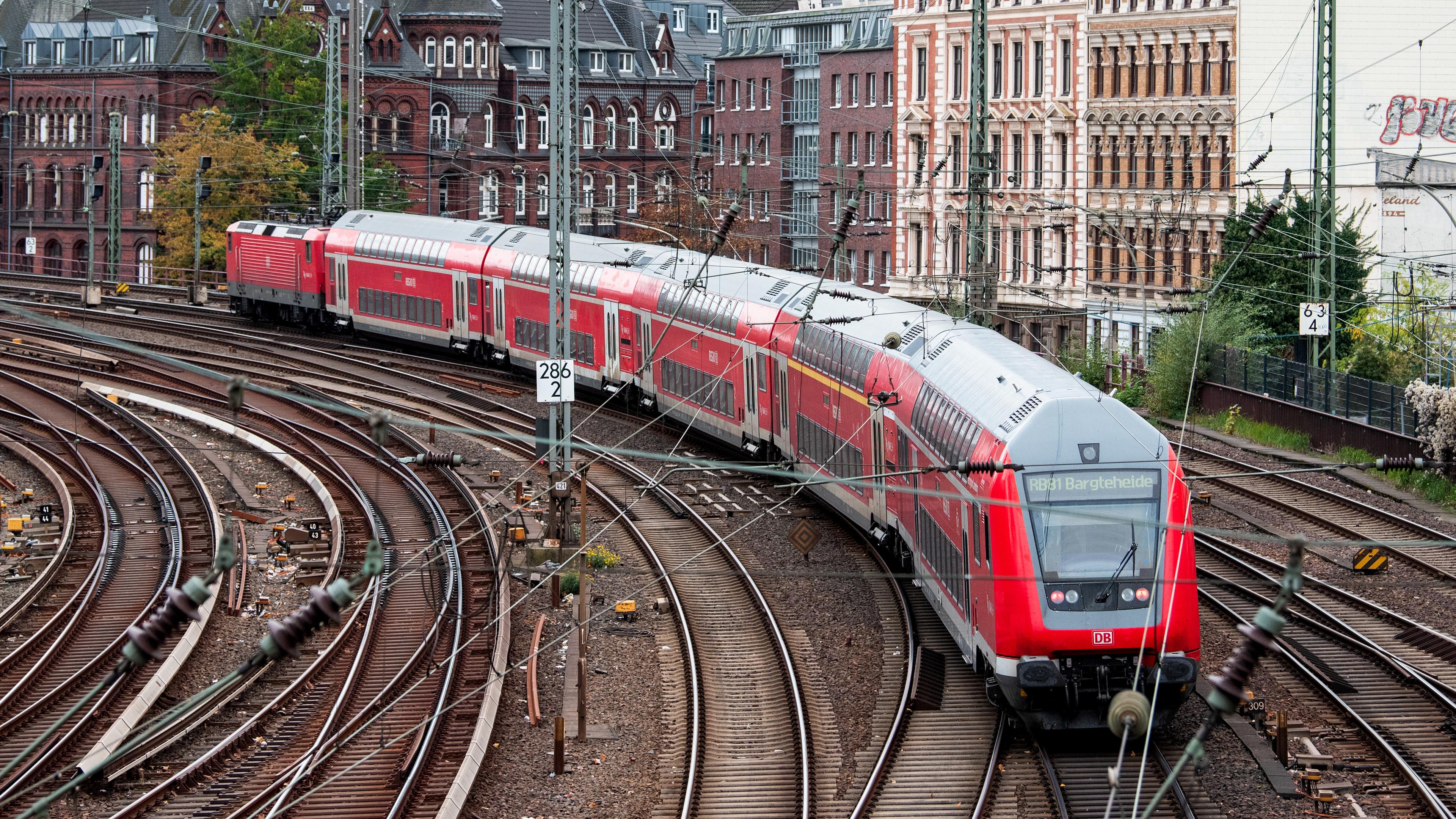 Eine Regionalbahn fährt an Häusern in der Stadt Hamburg vorbei. 