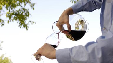 Wein aus Dekantierkaraffe wird in Wein-Glas eingegossen