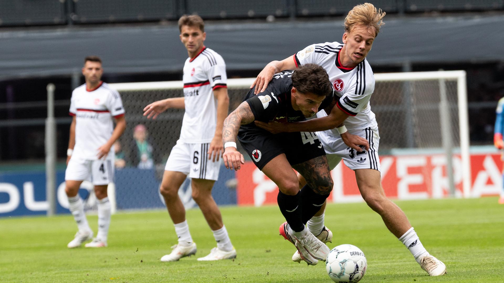 Viktoria Kölns Niklas Castelle im Zweikampf mit 1. FC Nürnbergs Tim Janisch (l-r) am 22.08.2026 in Köln. 