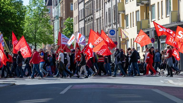 Ein Demozug mit dem Motto "Erst unsere Jobs, dann eure Profite" zieht durch die Stadt. 
