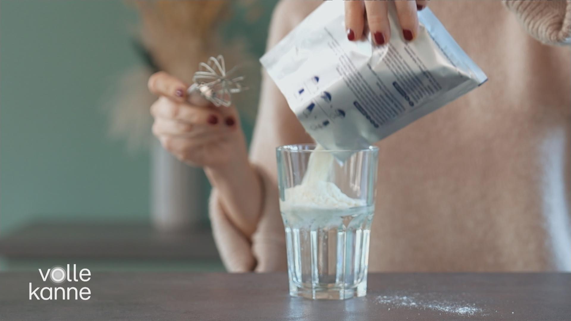 Eine Frau schüttet Pulver in ein Getränk