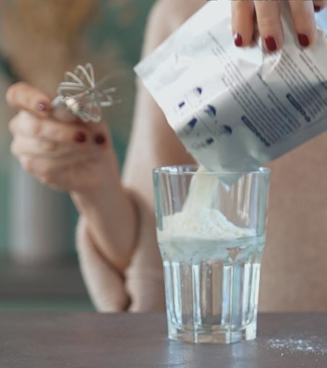 Eine Frau schüttet Pulver in ein Getränk