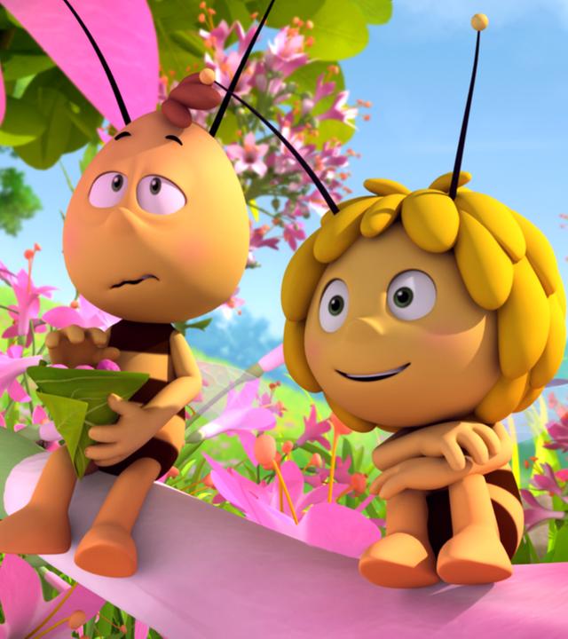 Maja (rechts) und Willi (links) sitzen auf einer Blume. Um sie herum sind viele rosafarbene Blüten. Die beiden blicken geradeaus, während Willi einen Snack in der Hand hält.