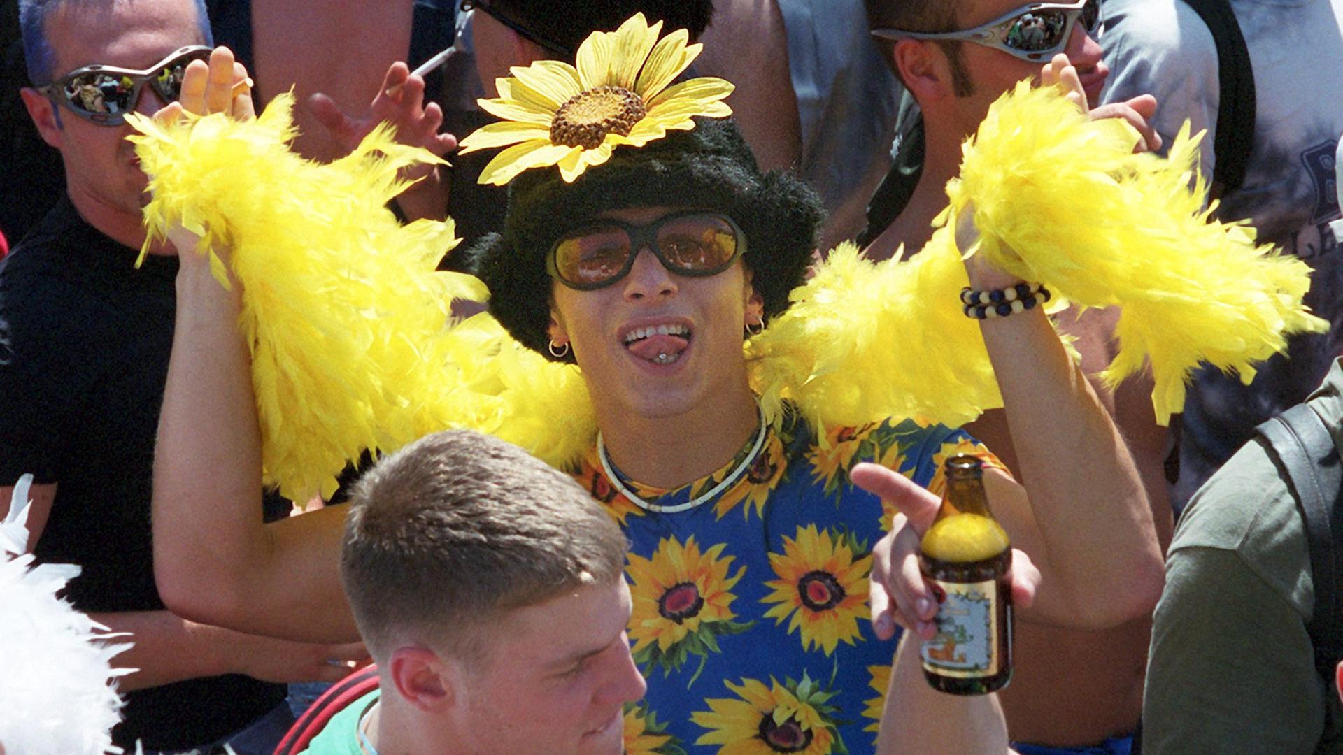"Die 90er: 1993-1996: Loveparade und Börsenfieber": Mit Sonnenblumenschmuck und gelber Boa tanzt ein Raver bei der Love Parade in Berlin, 1999.