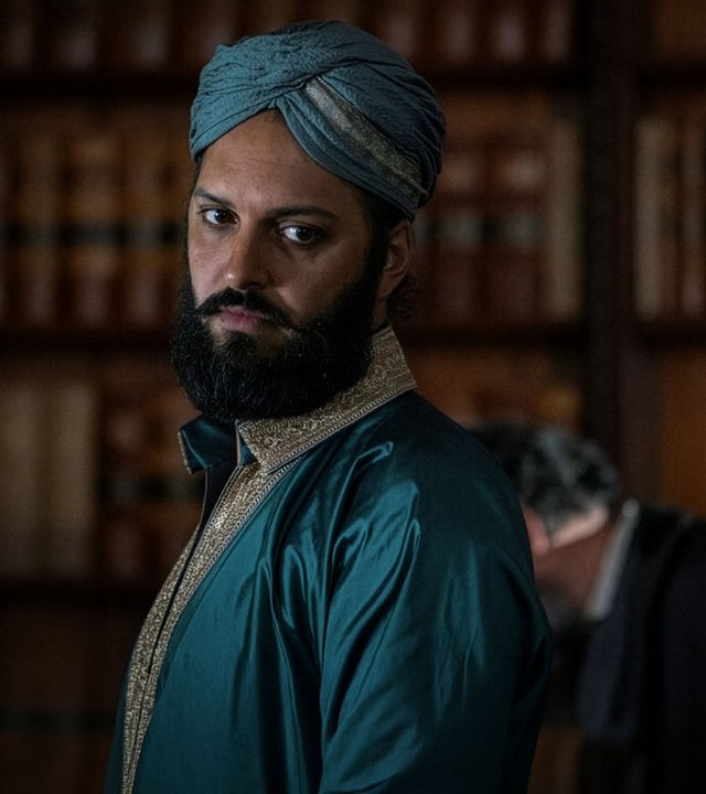 "Nautilus - Die Aktionäre": Nemo (Shazad Latif) steht in einem Raum vor einem Bücherregal. Er trägt elegante indische Kleidung und einen Dastar als Kopfbedeckung.