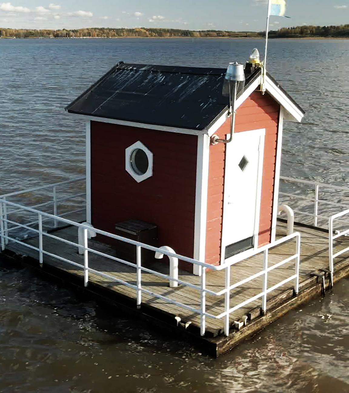 Eine kleine Blockhütte schwimmt auf einer Veranda in einem Fluss.