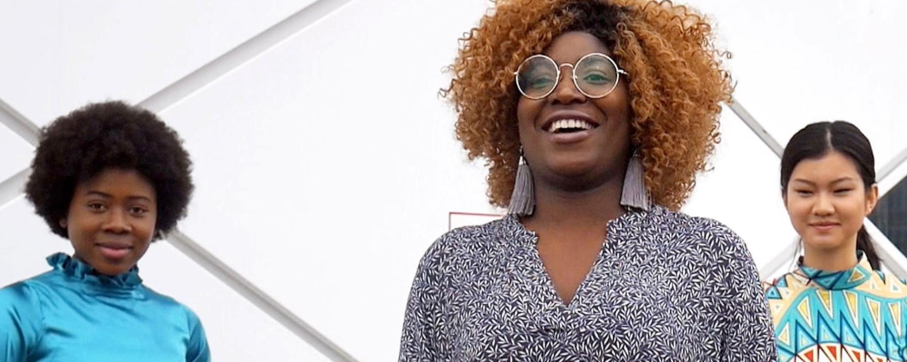 Faourouz lächelt, hinter ihr sind zwei ihrer Models zu sehen.