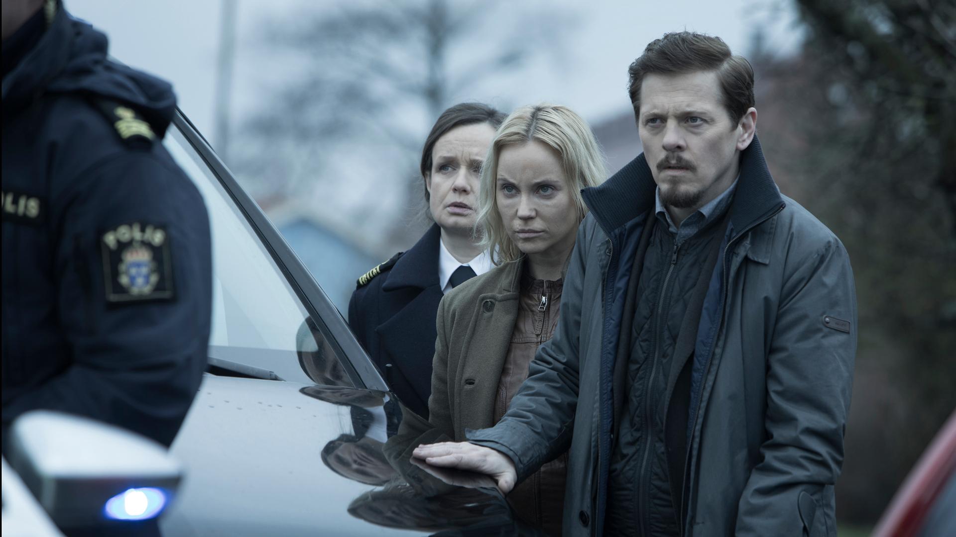 Die Brücke - Das Finale (4): Henrik (Thure Lindhardt), Saga (Sofia Helin) und Linn (Maria Kulle) stehen hinter einem Auto und beobachten den Zugriff des Sonderkommandos.