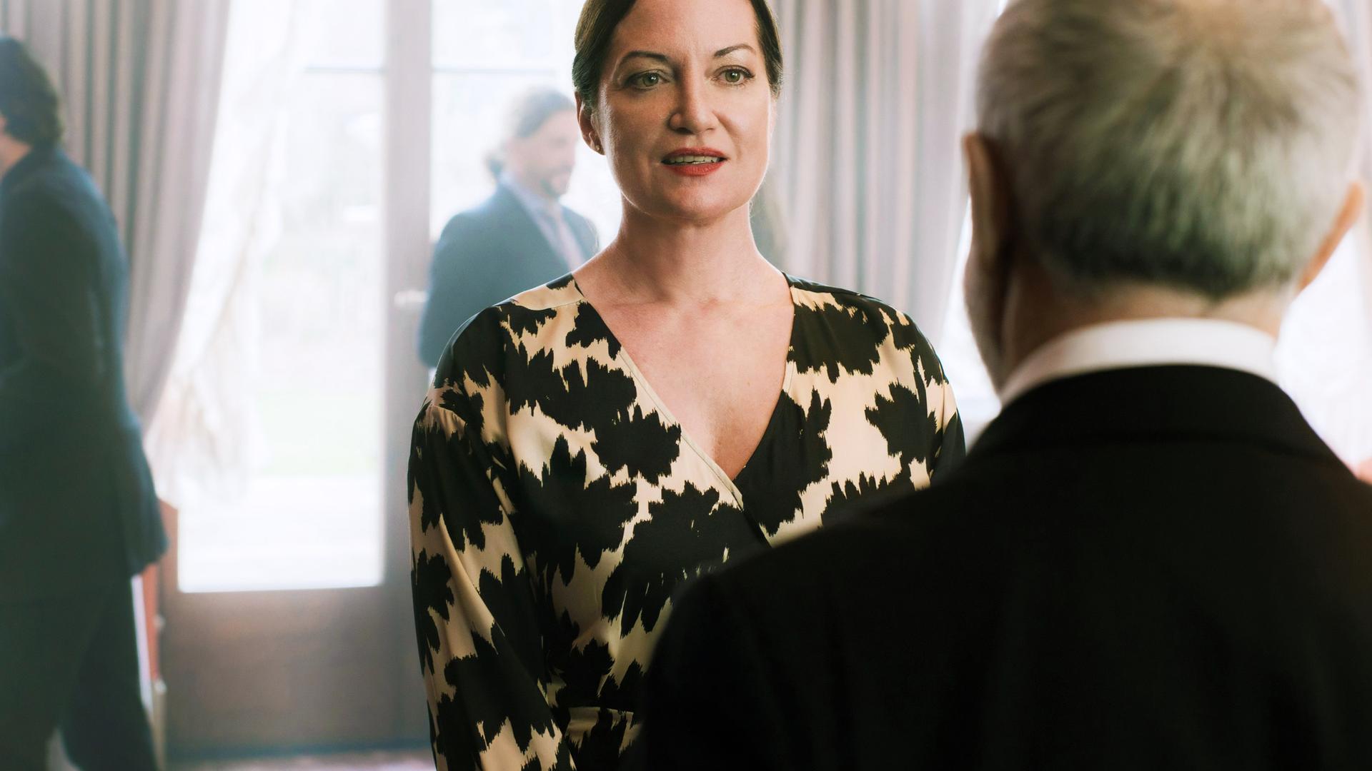 Eine Frau und ein Mann unterhalten sich. Der Mann steht mit dem Rücken zur Kamera.