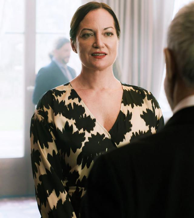 Eine Frau und ein Mann unterhalten sich. Der Mann steht mit dem Rücken zur Kamera.