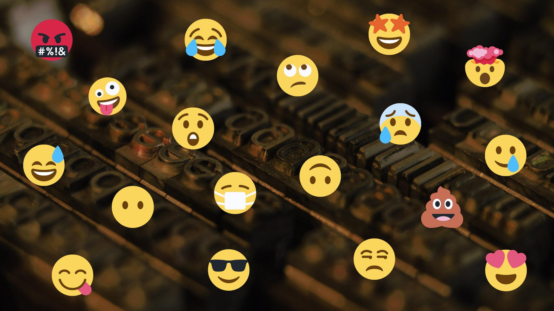 Viele verschiedene Emojis montiert über einen Druckersatz von kleinen Buchstaben