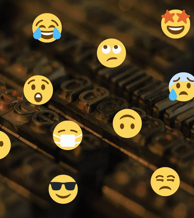 Viele verschiedene Emojis montiert über einen Druckersatz von kleinen Buchstaben