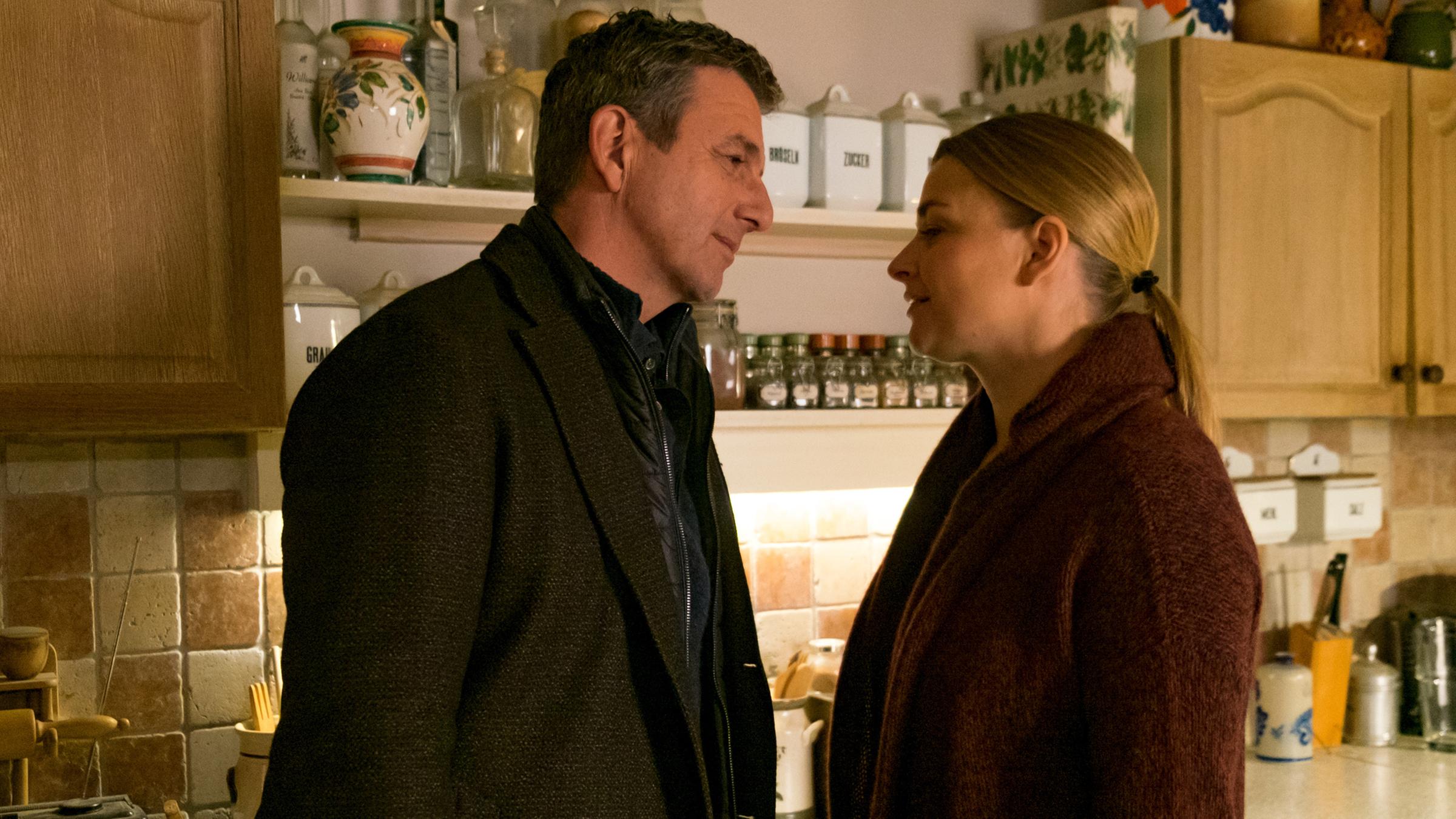 Martin (Hans Sigl) und Anne (Ines Lutz) stehen sich in der Küche dicht gegenüber. Ihre Hände liegen auf der Arbeitsplatte übereinander.