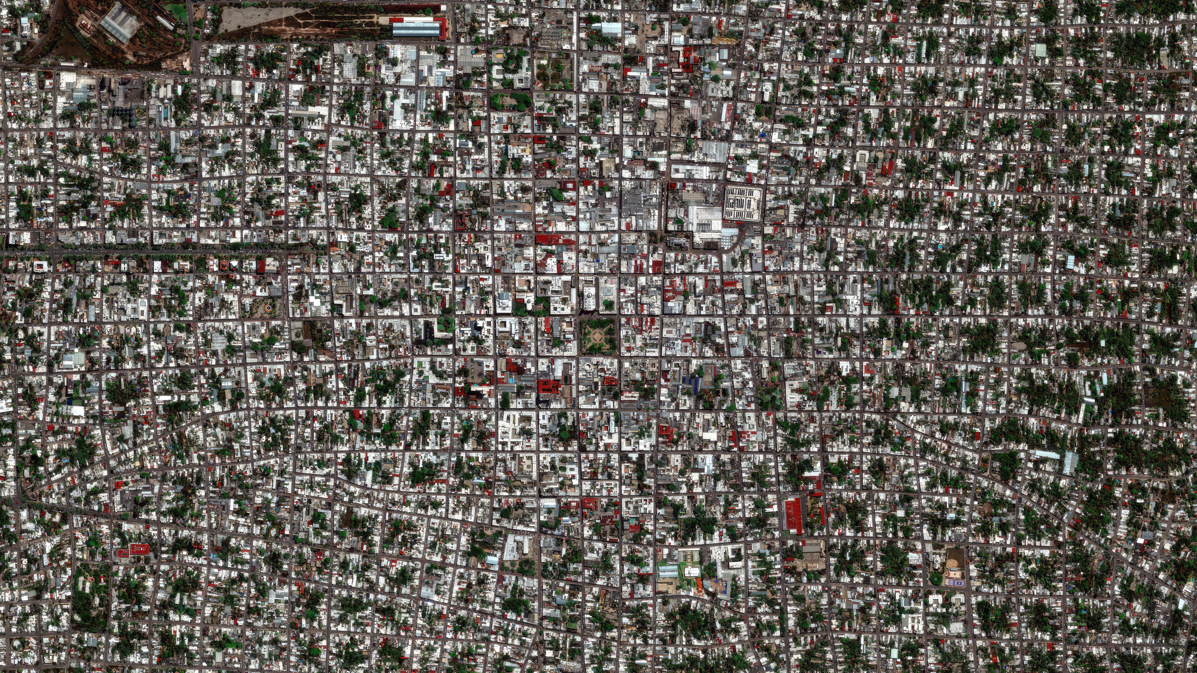 Luftaufnahme einer Großstadt, die durch Straßen und Gebäude in regelmäßige geometrische Formen geteilt ist.
