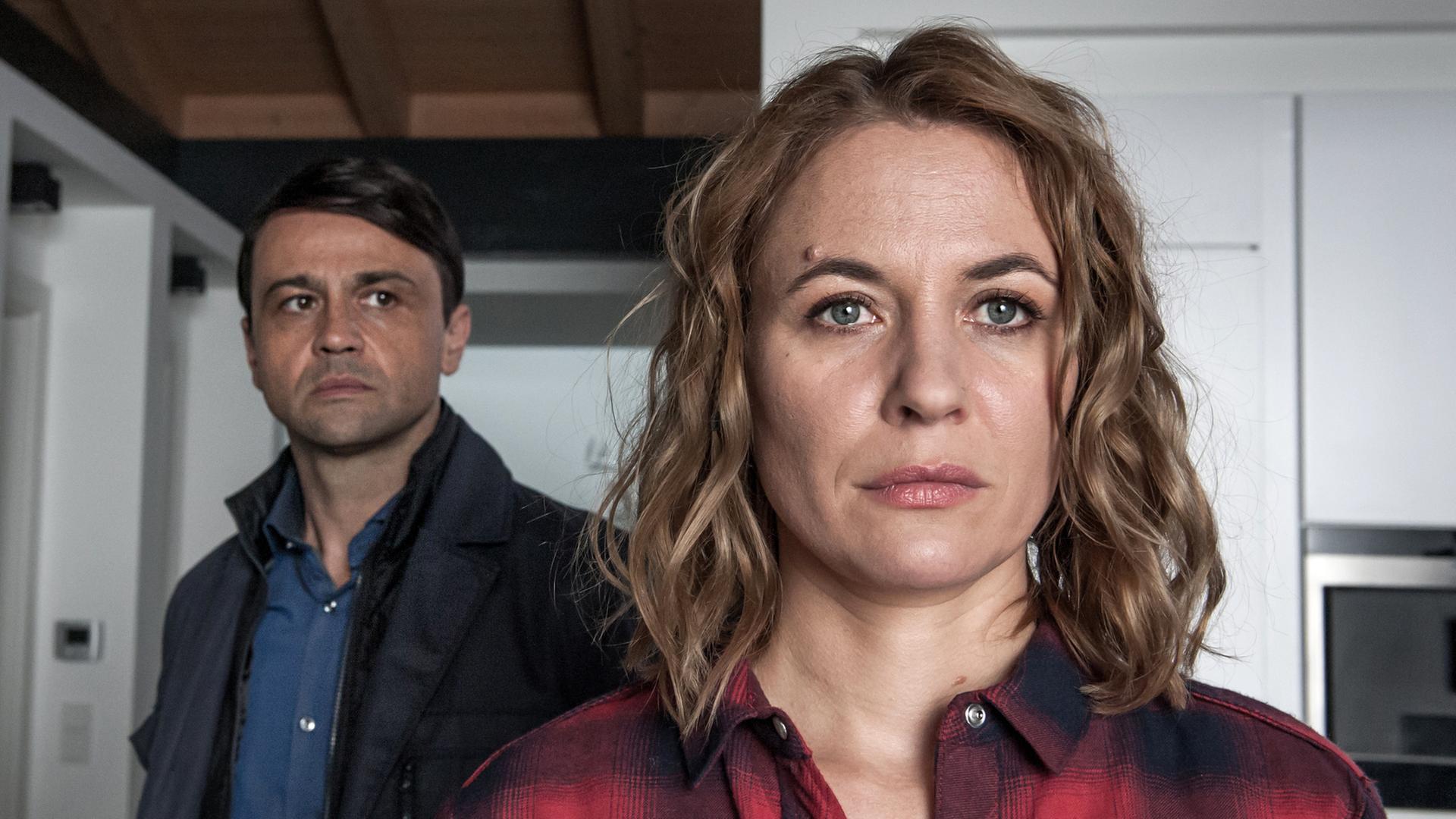 "Der Bergdoktor - Die falsche Frau (2)": Kerstin Rensing (Julia Thurnau) blickt mit ernstem Gesichtsausdruck in die Ferne. Ihr Mann Jakob (Michael Rotschopf) steht mit verlorenem Blick hinter ihr.