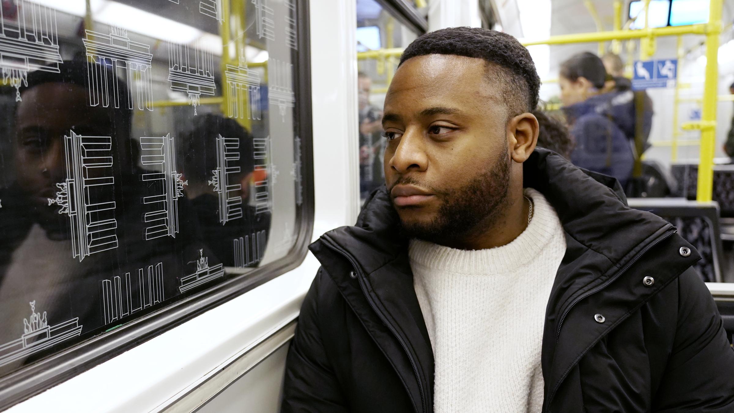Alltagsrassismus in Deutschland": Cedric geht die Treppe einer U-Bahn-Station hoch. Andere Menschen laufen die Treppe hoch und runter.