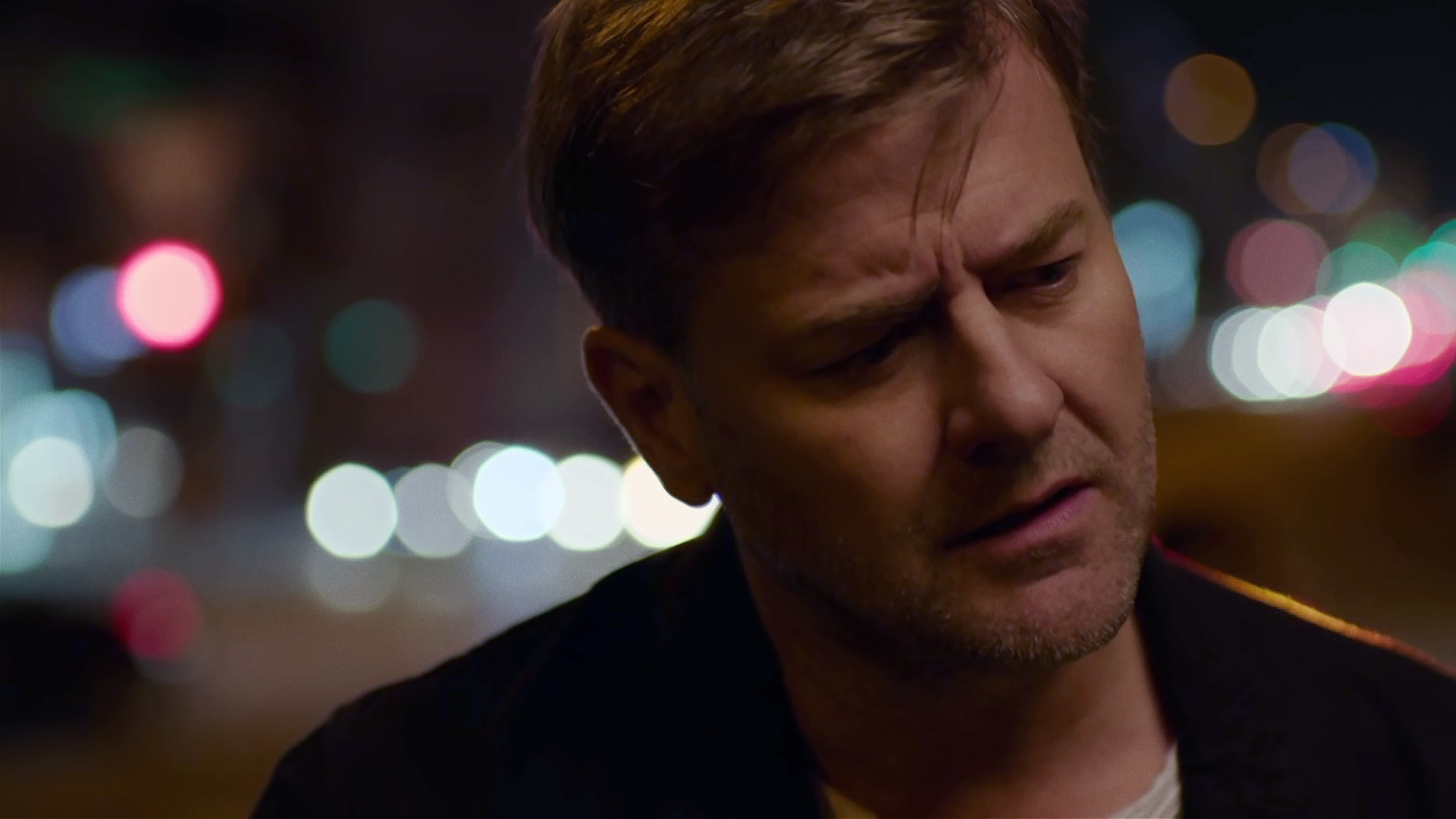 Großaufnahme von Harald Neuhauser (Marcus Mittermeier) nachts auf einer Straße. Er hält den Kopf schräg und schaut nachdenklich. 