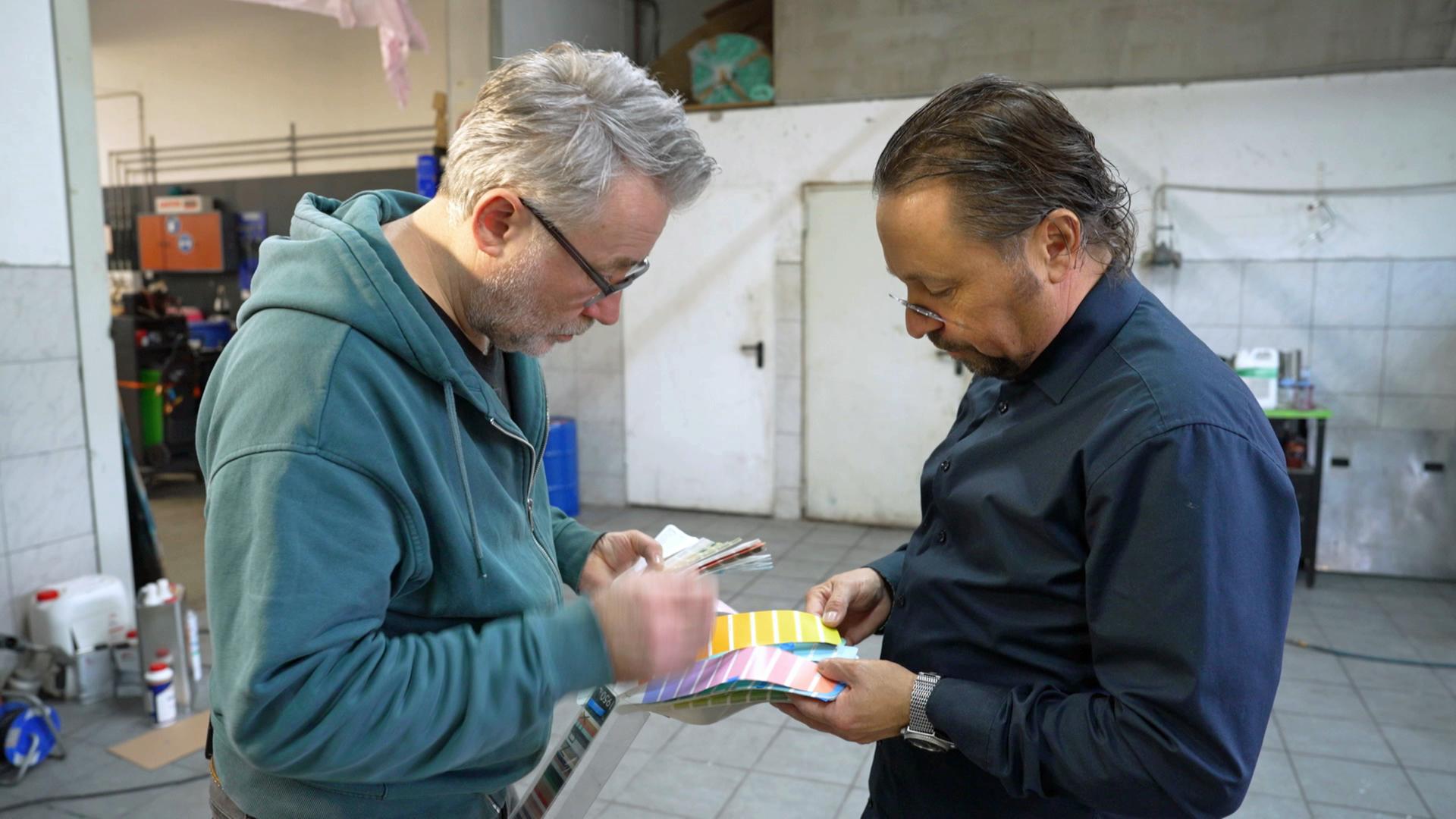 Jan Čížek und Wolfgang Pauritsch schauen sich gemeinsam eine Farbpalette für die neue Farbe ihrer Schachpyramide an.