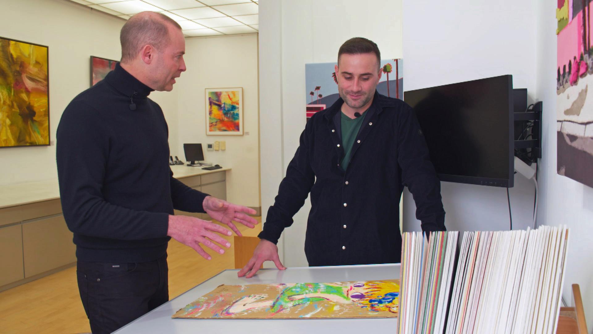 Händler David Suppes wird bezüglich der Rahmung eines farbenfrohen Gemäldes von Ayako Rokkaku fachmännisch beraten.